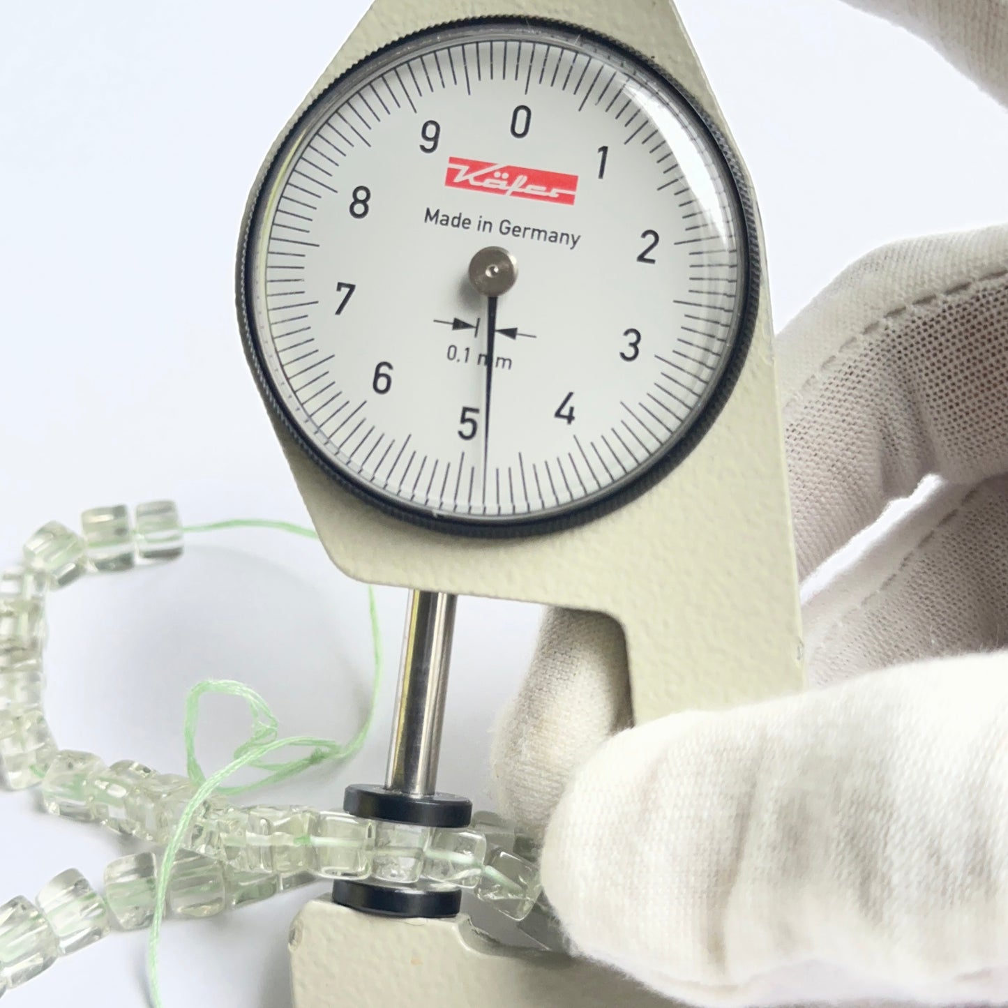 A dial gauge measures the green amethyst smooth cube 4.5–5mm gemstone.