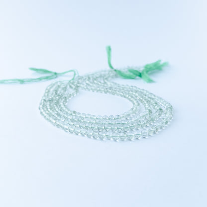 Green Amethyst smooth round gemstone beads in soft green tones arranged on a 33cm strand for handmade jewellery components.