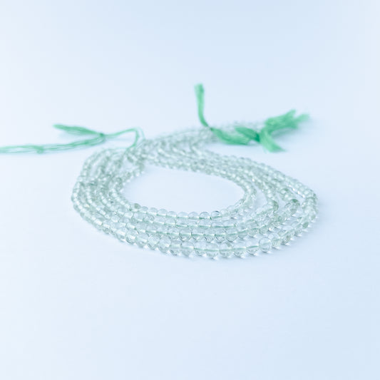 Green Amethyst smooth round gemstone beads in soft green tones arranged on a 33cm strand for handmade jewellery components.