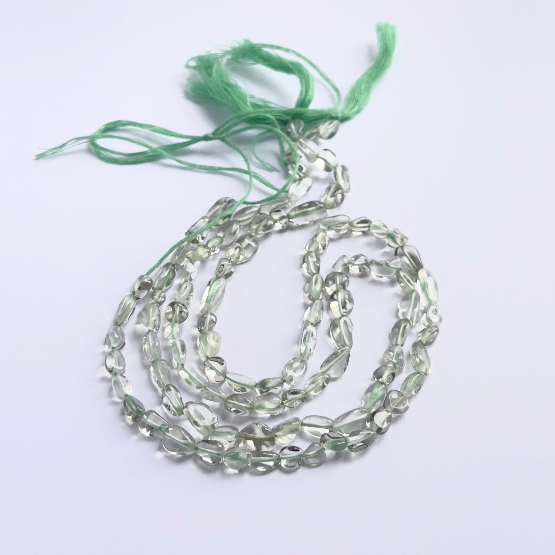 Stone beads in a strand of Green Amethyst, highlighting their smooth tumbles and 5–6mm size.