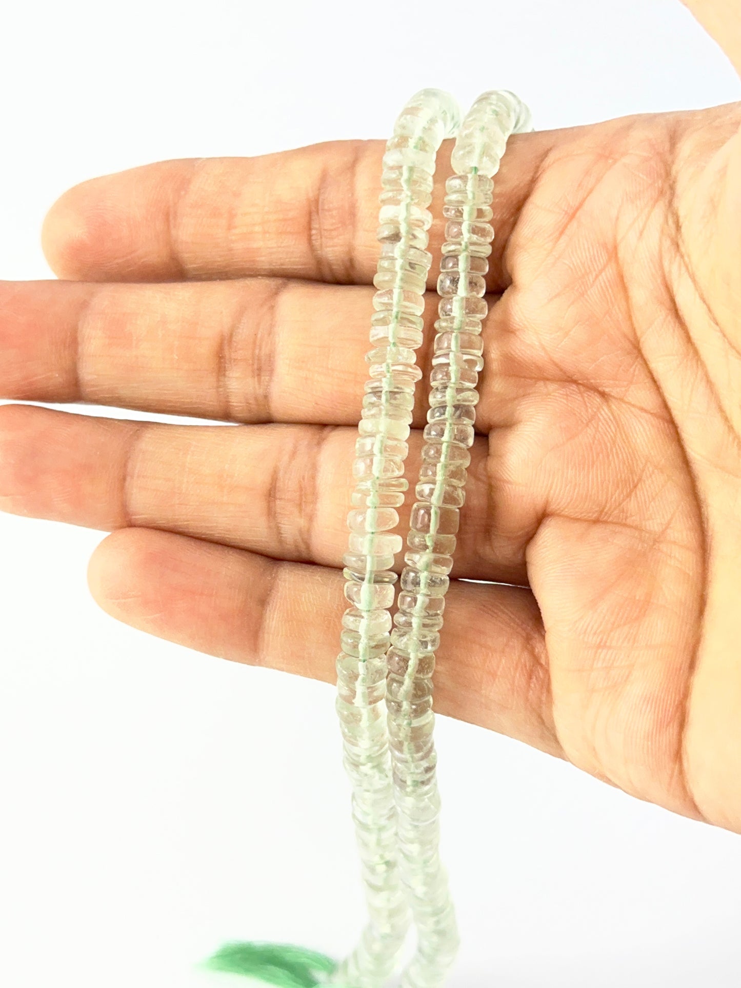 Hand holding high-clarity amethyst wheel beads, 5.5–6.0mm, displayed on a 21cm strand.