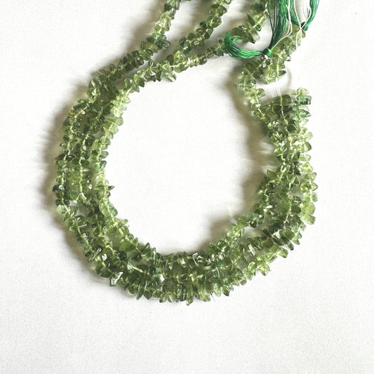 Close-up of polished Green Apatite chips arranged with gentle curves and varied