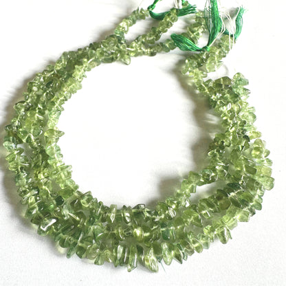 Glossy Green Apatite gemstone chips catching light to reveal their crystal texture.