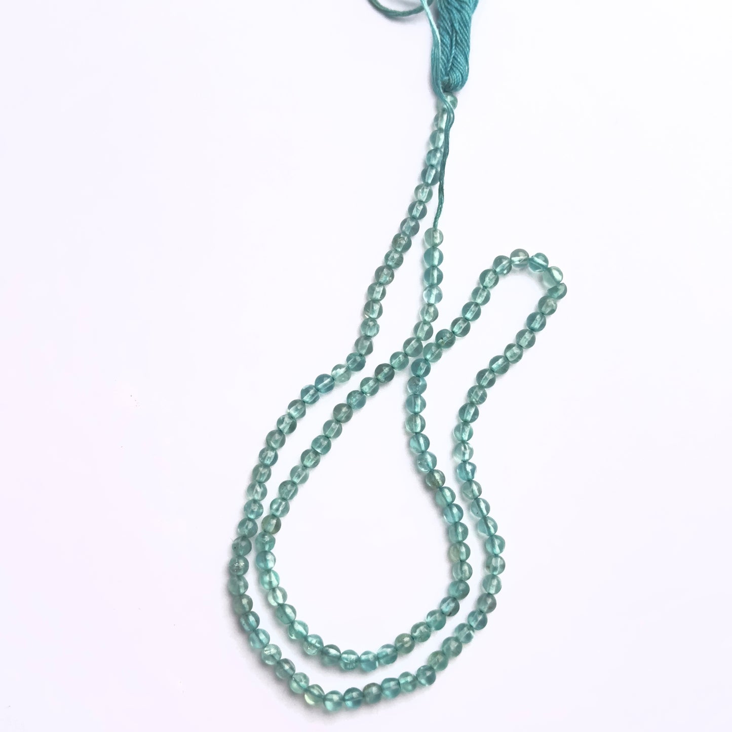 Stone beads in Apatite finish laid flat to highlight their 3mm size and smooth cut.