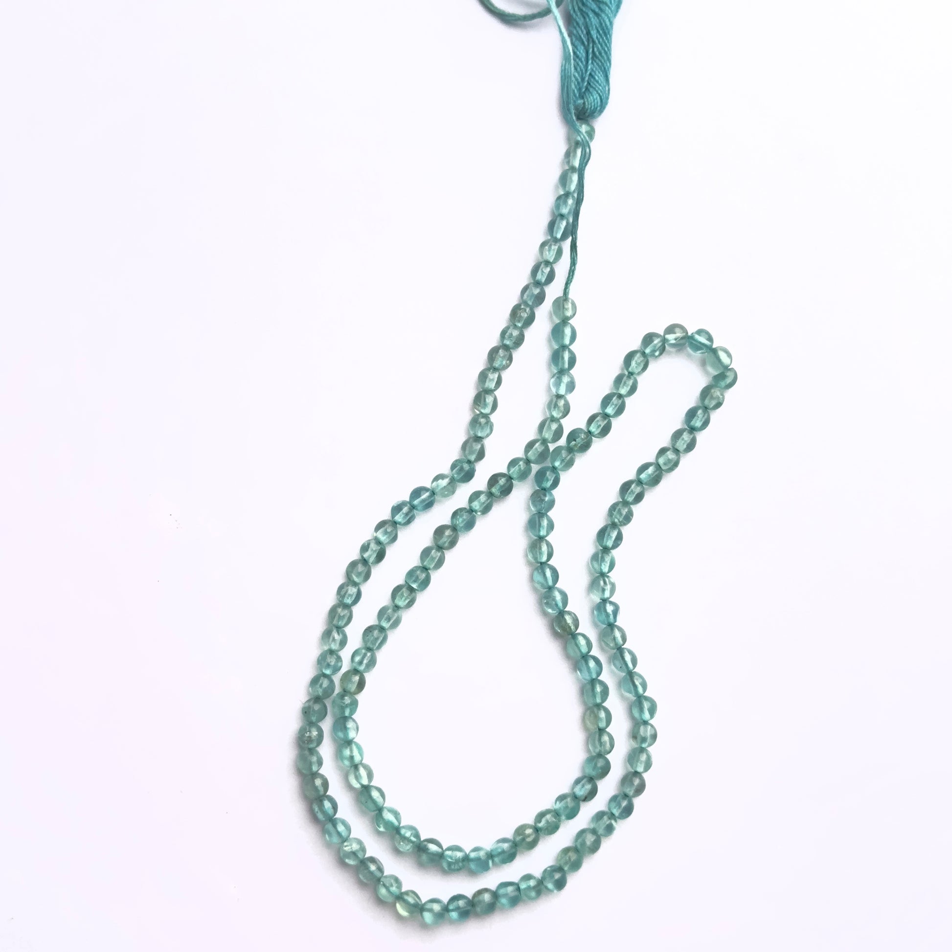 Stone beads in Apatite finish laid flat to highlight their 3mm size and smooth cut.