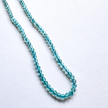 Close-up of 3mm Green Apatite beads arranged on a strand, showcasing clarity and colour.