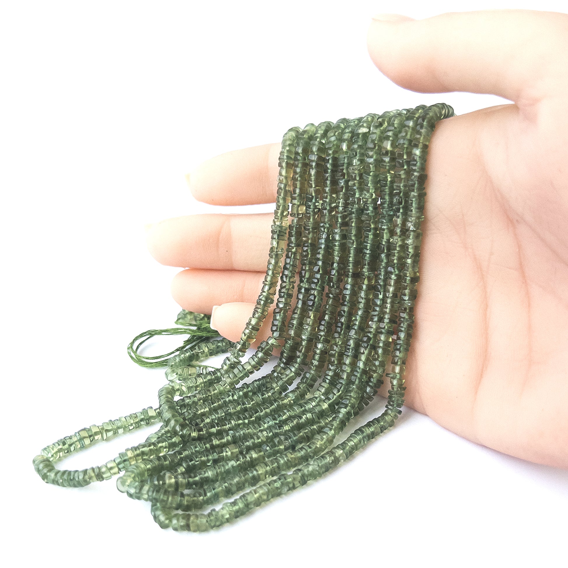 A person holds delicate strands of Green Apatite beads, showcasing their smooth wheel design.