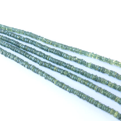 Close‑up of Green Apatite smooth wheel beads showing their glow, cut precision and bright green translucency.