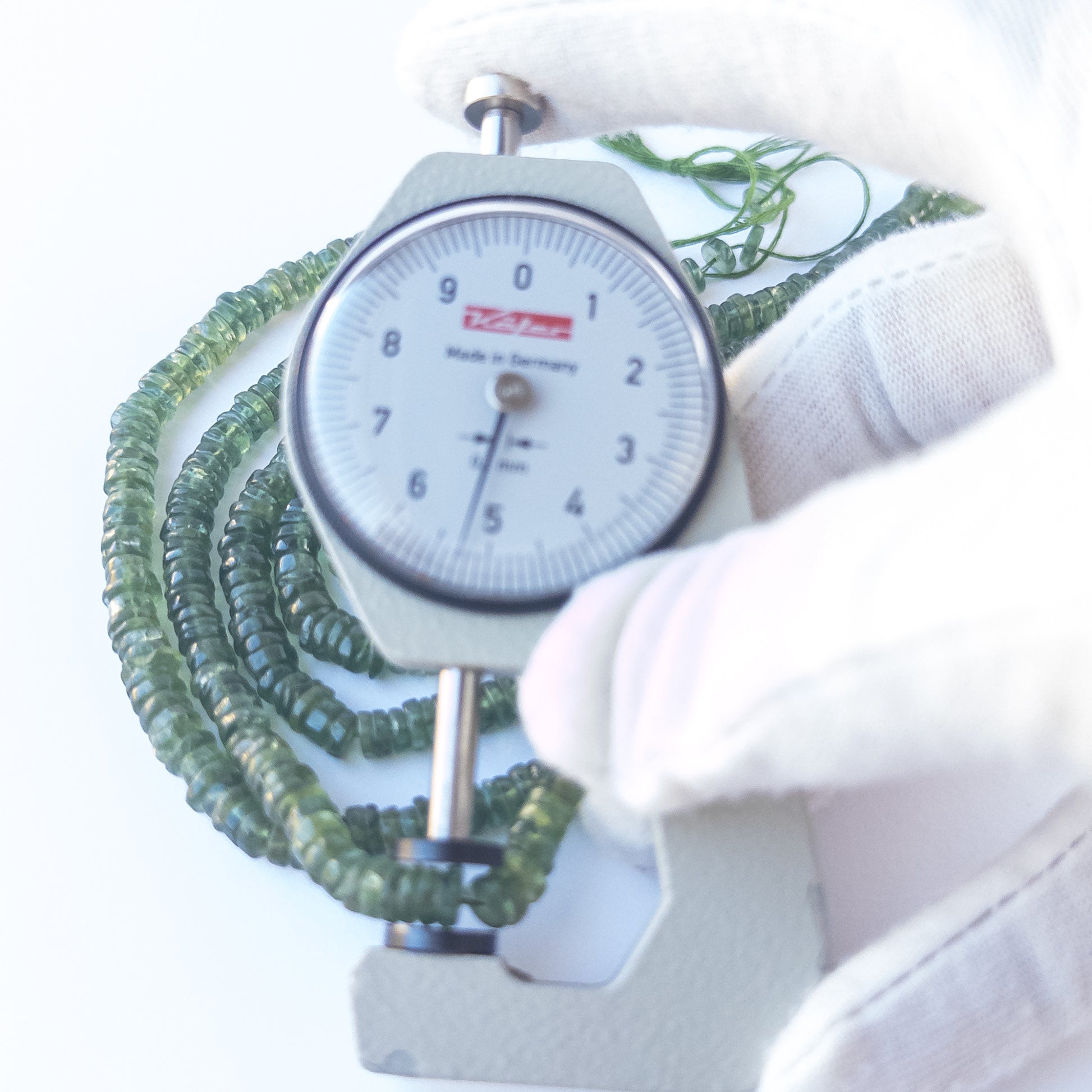 A dial gauge measures the Green Apatite smooth wheel 5.3–5.5mm gemstone.