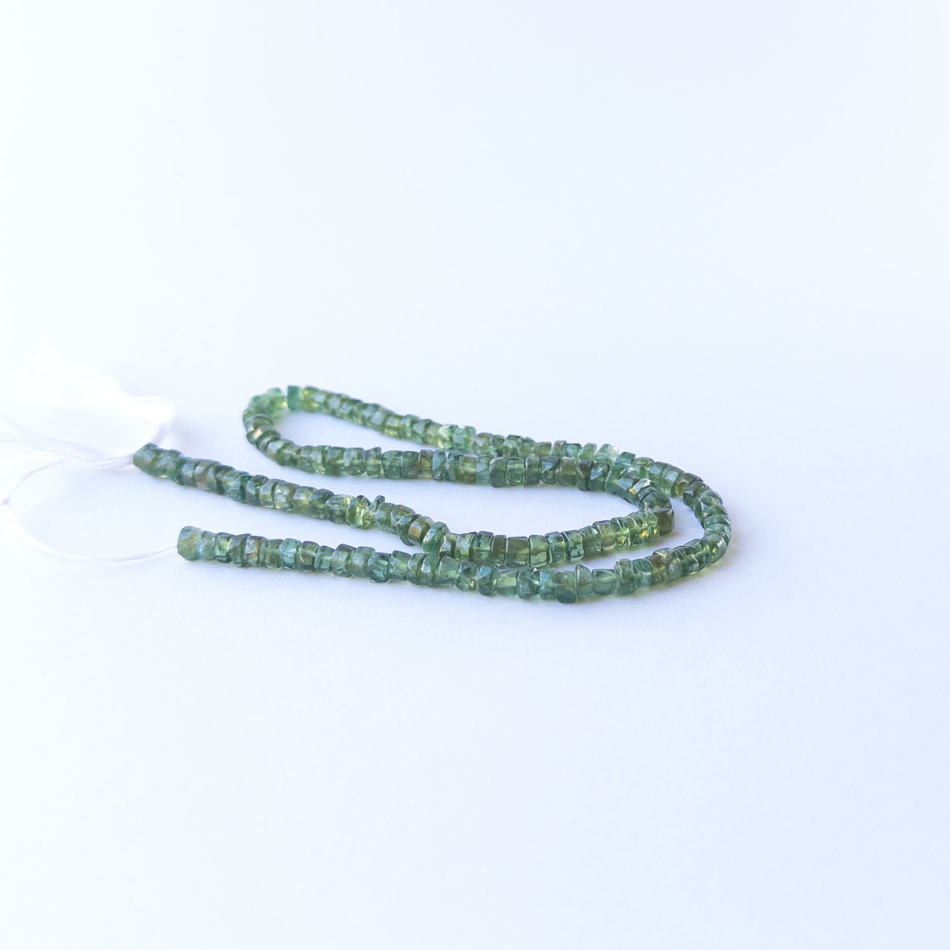 Premium Green Apatite smooth wheel gemstone beads arranged neatly in a long 34cm strand.