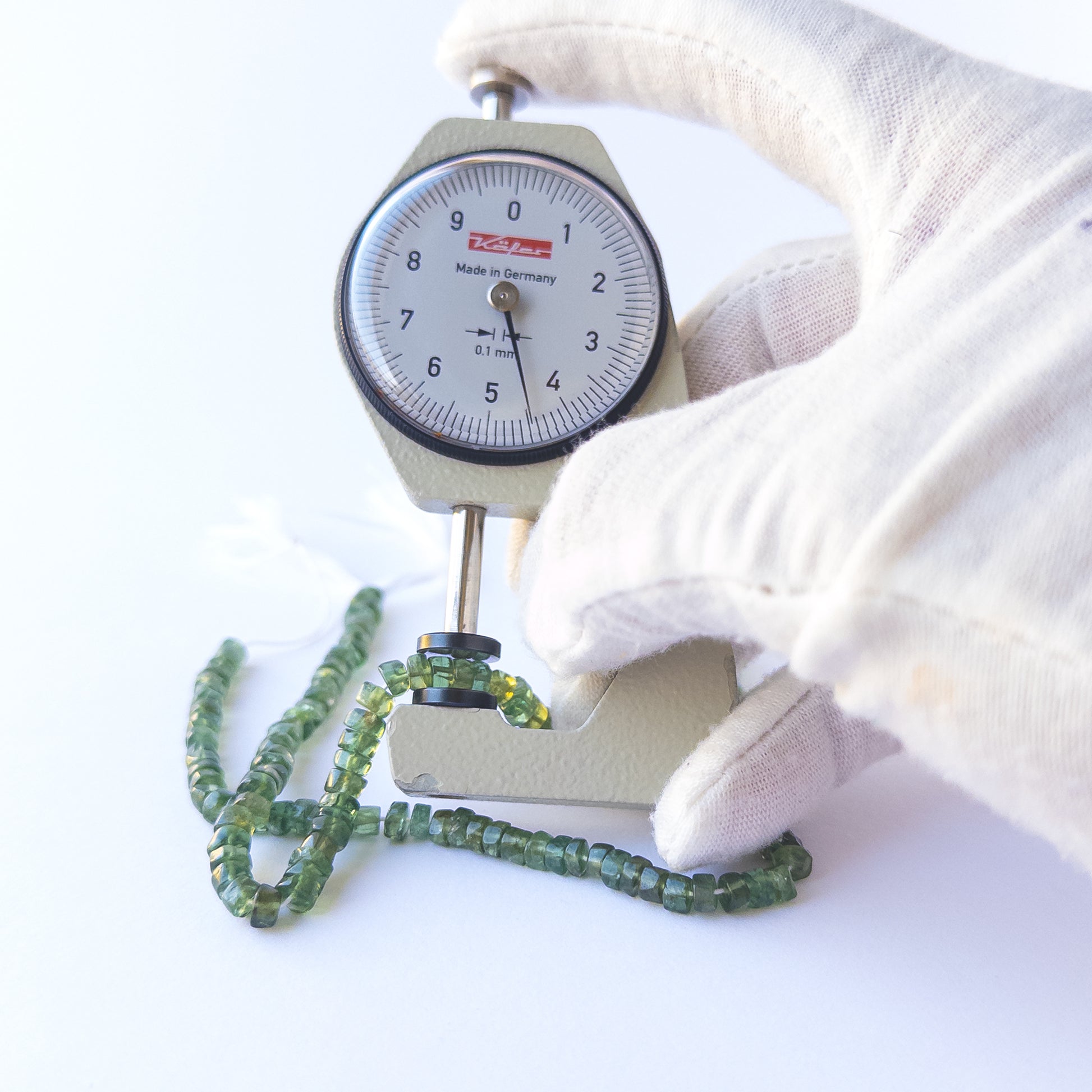 A dial gauge measures the Green Apatite smooth wheel 4.5–4.6mm gemstone.