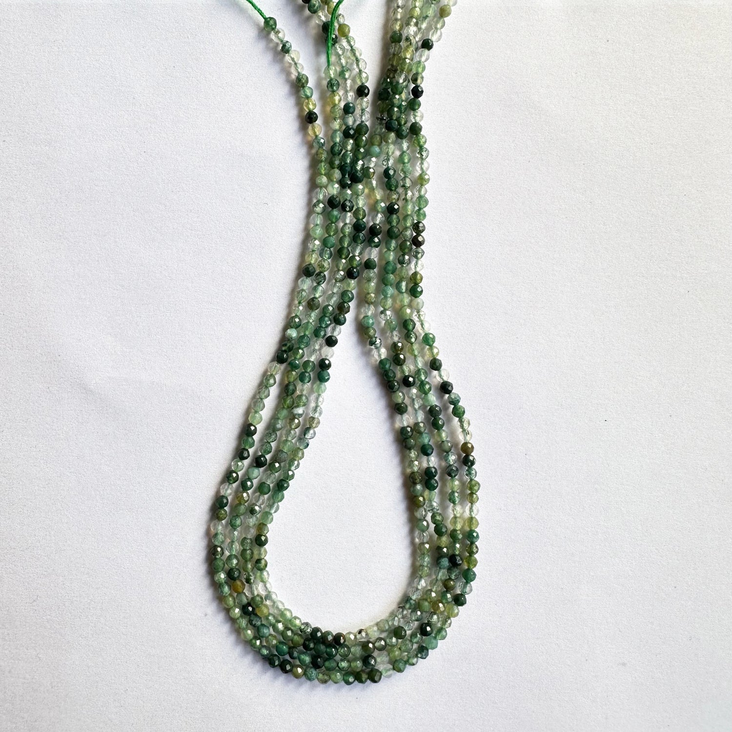 Close-up of green aventurine faceted rondelle beads highlighting their translucent green tones and fine cut.