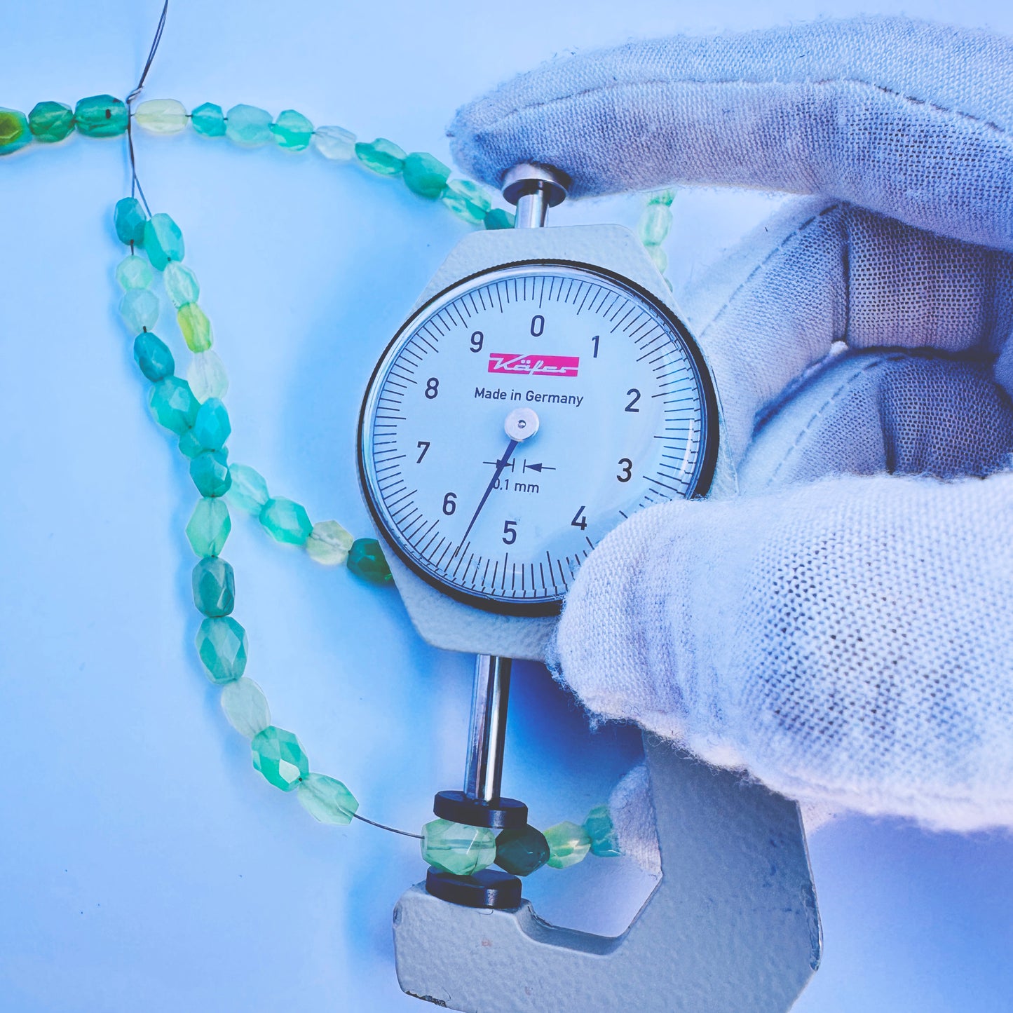 A dial gauge measures the Green Chalcedony faceted oval 5mm gemstone.