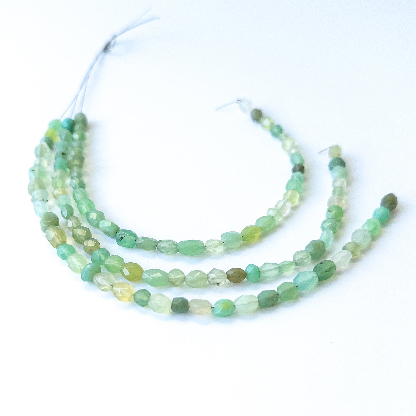Genuine Green Chalcedony gemstone beads showcasing faceted oval cuts arranged neatly on a 20cm strand.