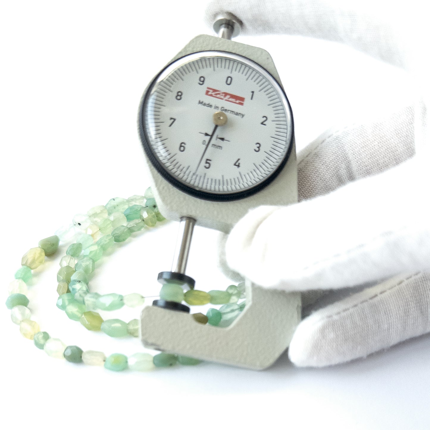 A dial gauge measures the Green Chalcedony faceted oval 4–7.5mm gemstone.