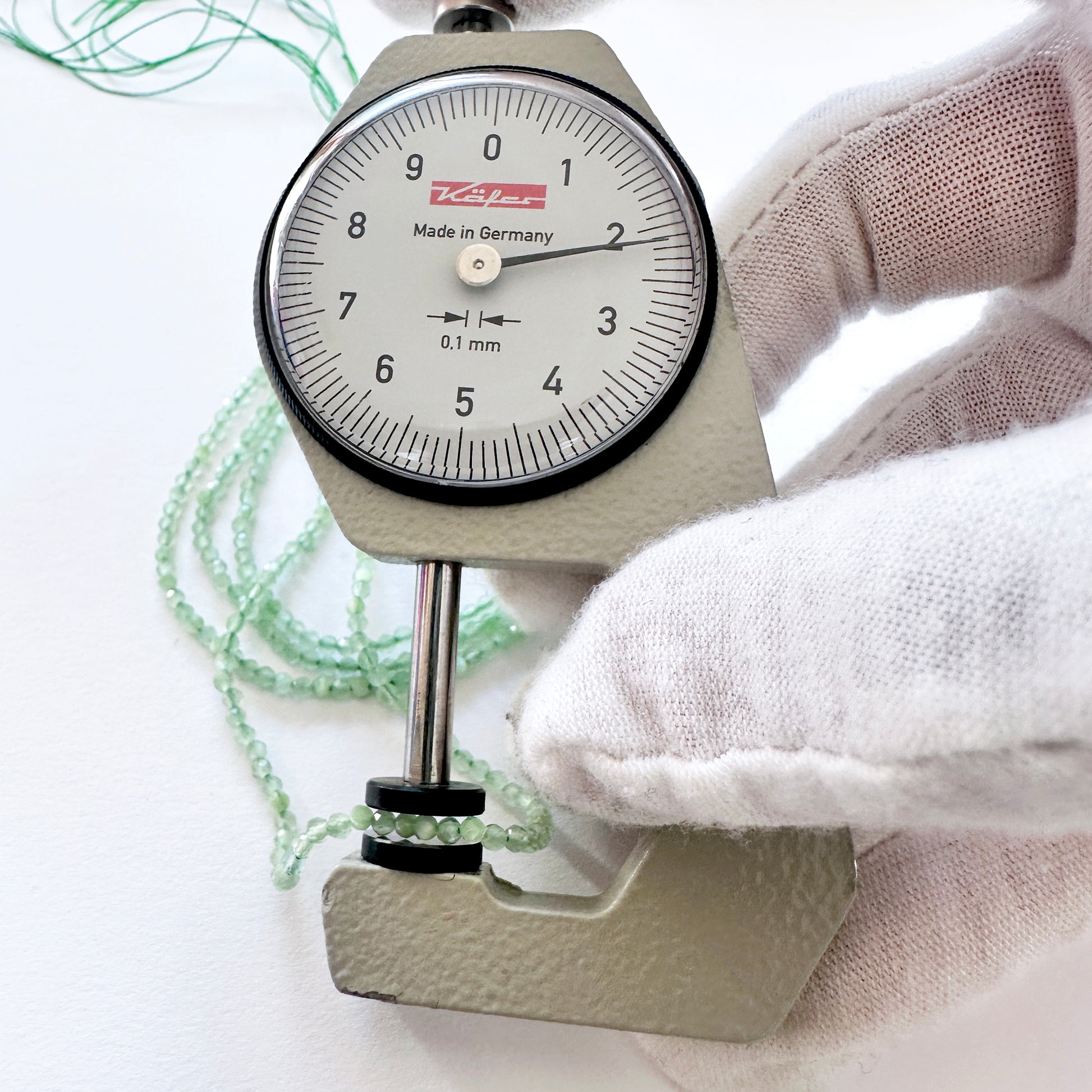 A dial gauge measures the Green Chalcedony faceted rondelle 2.1-2.2mm gemstone.