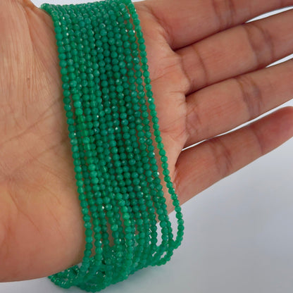 A person holds delicate strands of Green Onyx beads, showcasing their micro‑faceted rondelle design