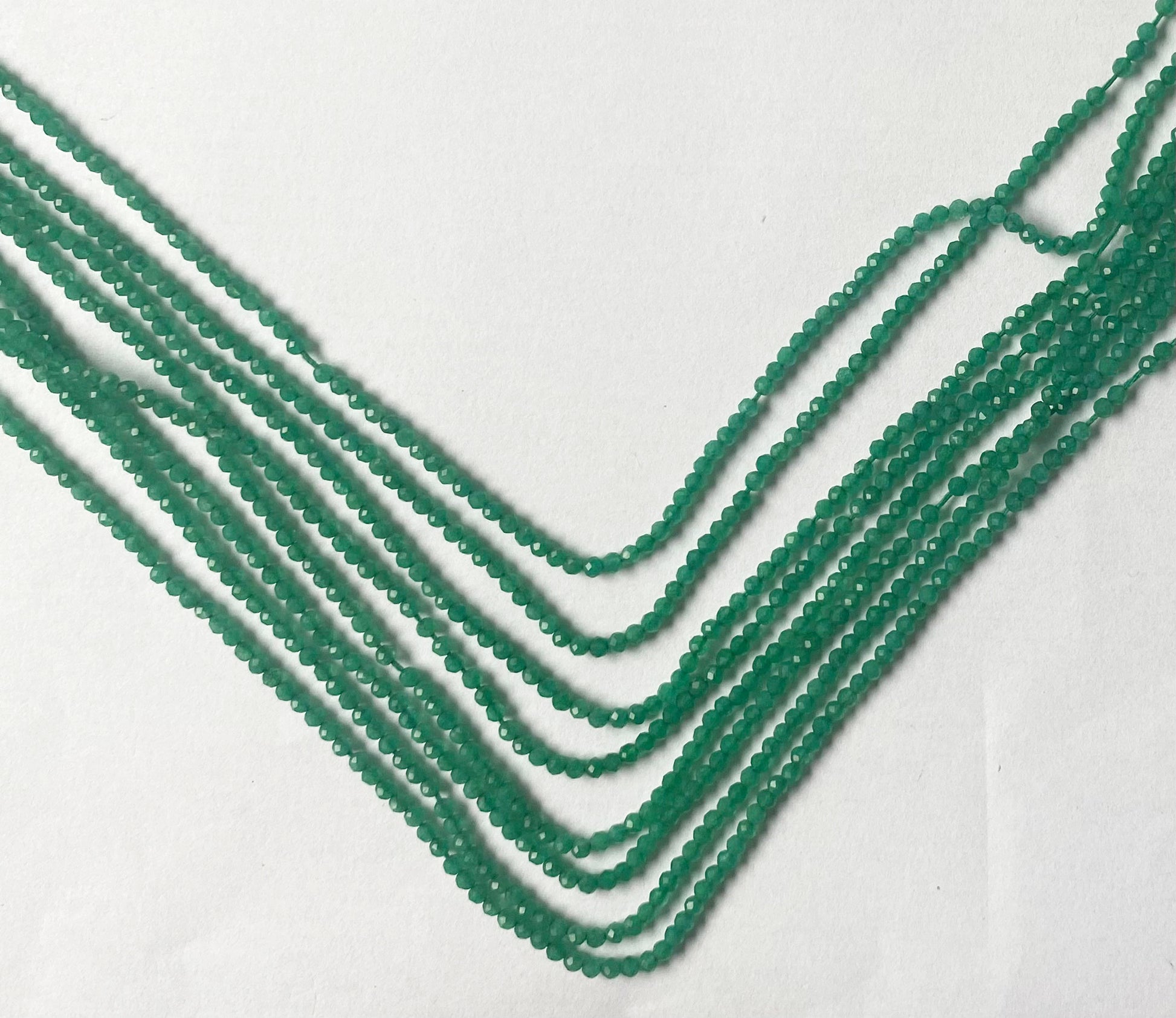 Radiant micro-faceted rondelle beads showcasing a brilliant emerald-green glow and refined shimmer.