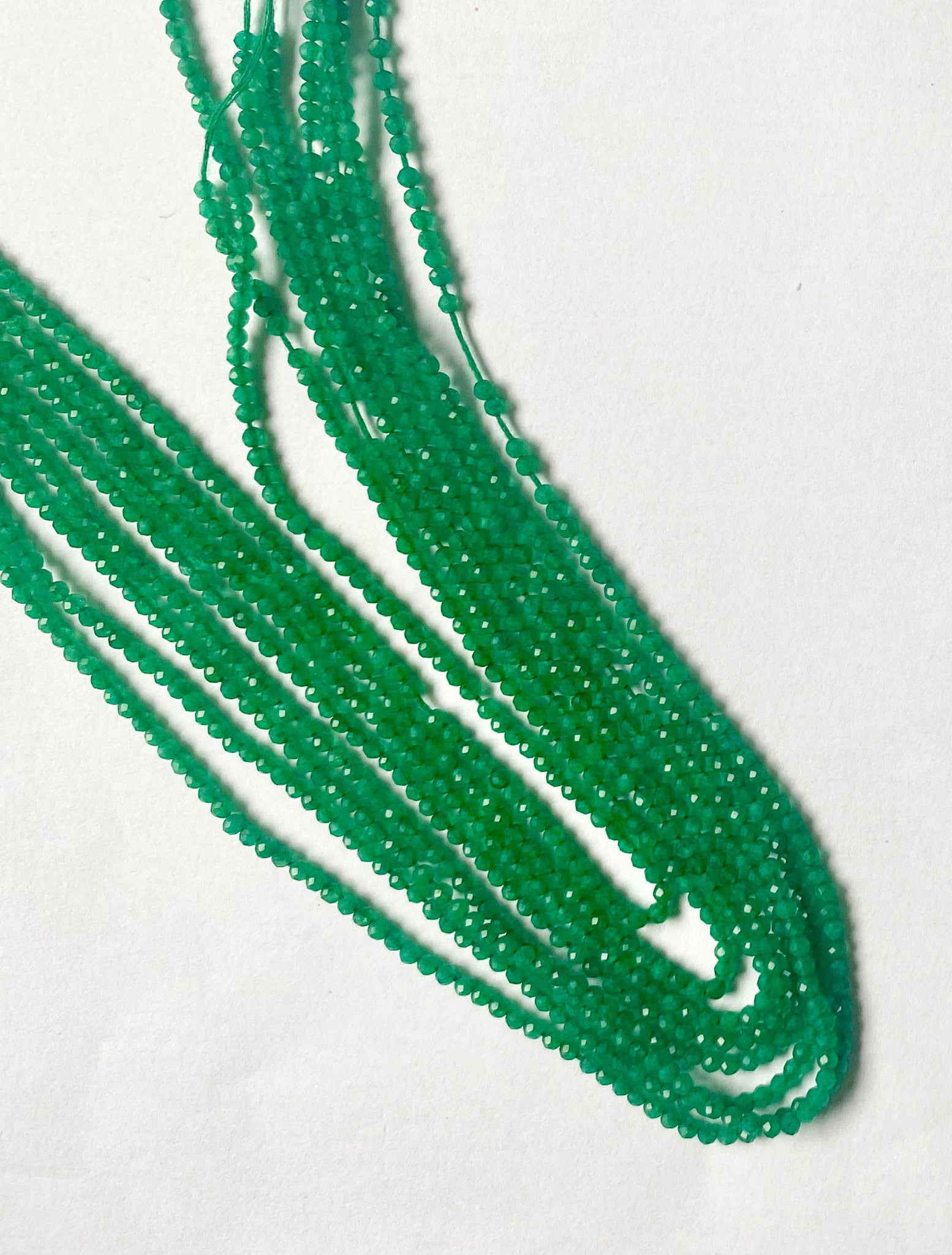 A close-up of Green Onyx beads displaying precise faceting and smooth edges.