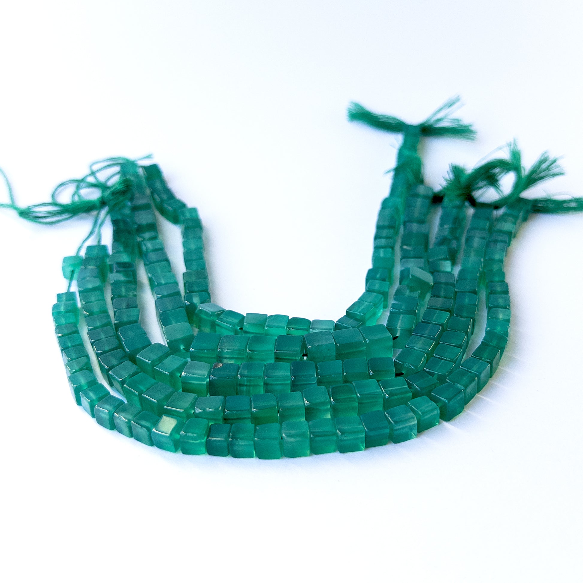 Handmade jewellery components featuring natural green onyx smooth cube beads in a neatly aligned strand.