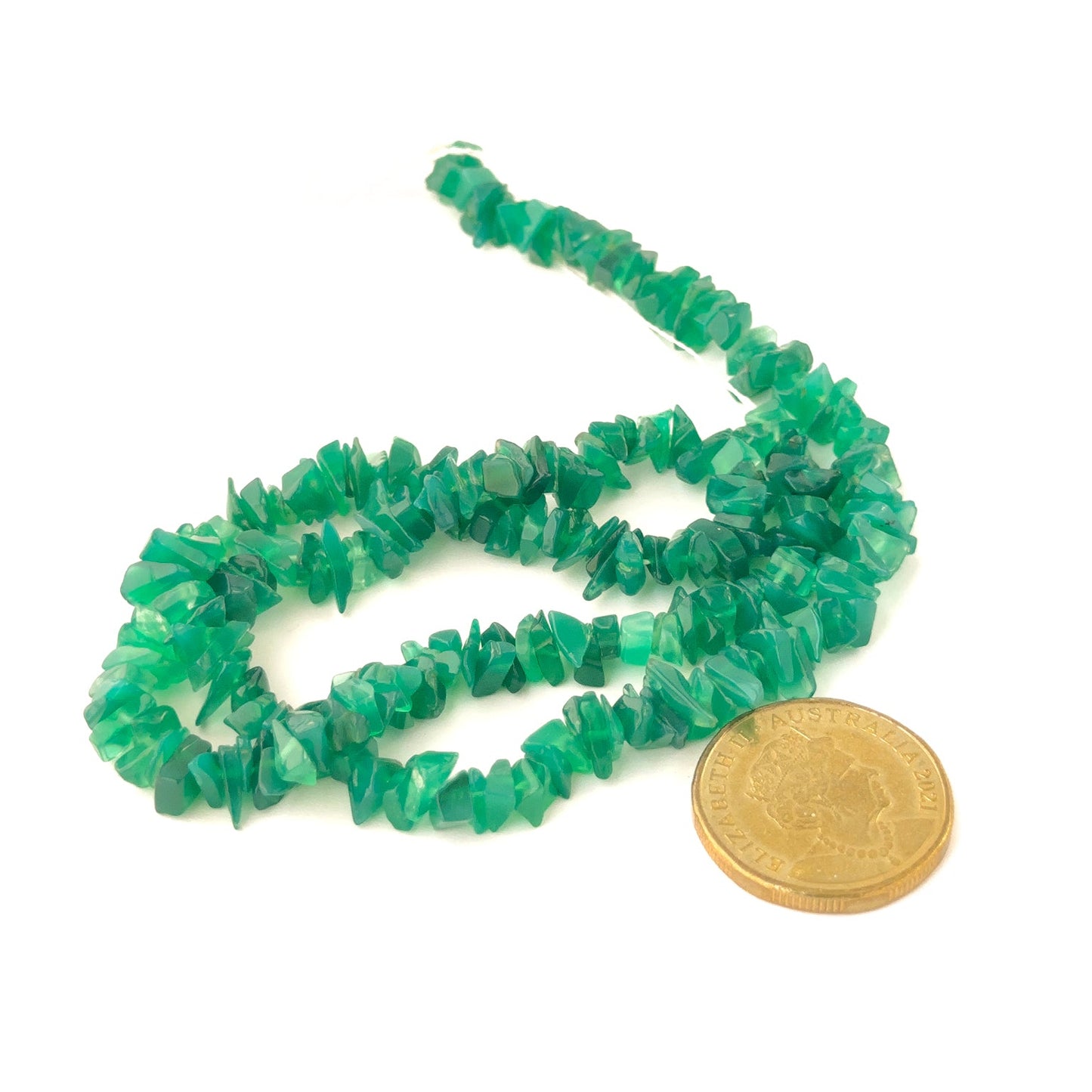 A coin places near handcrafted strand of natural Green Onyx chip beads, 5–10mm, for scale.