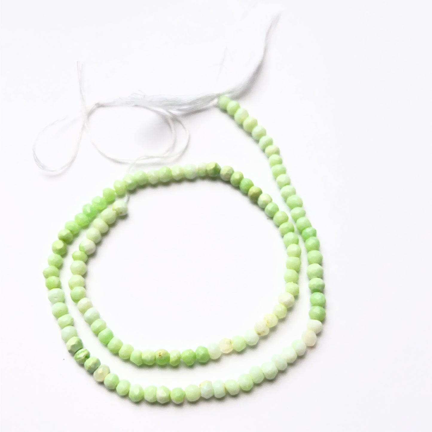 Green opal faceted rondelle beads sized 3.8–4mm showing natural colour variation