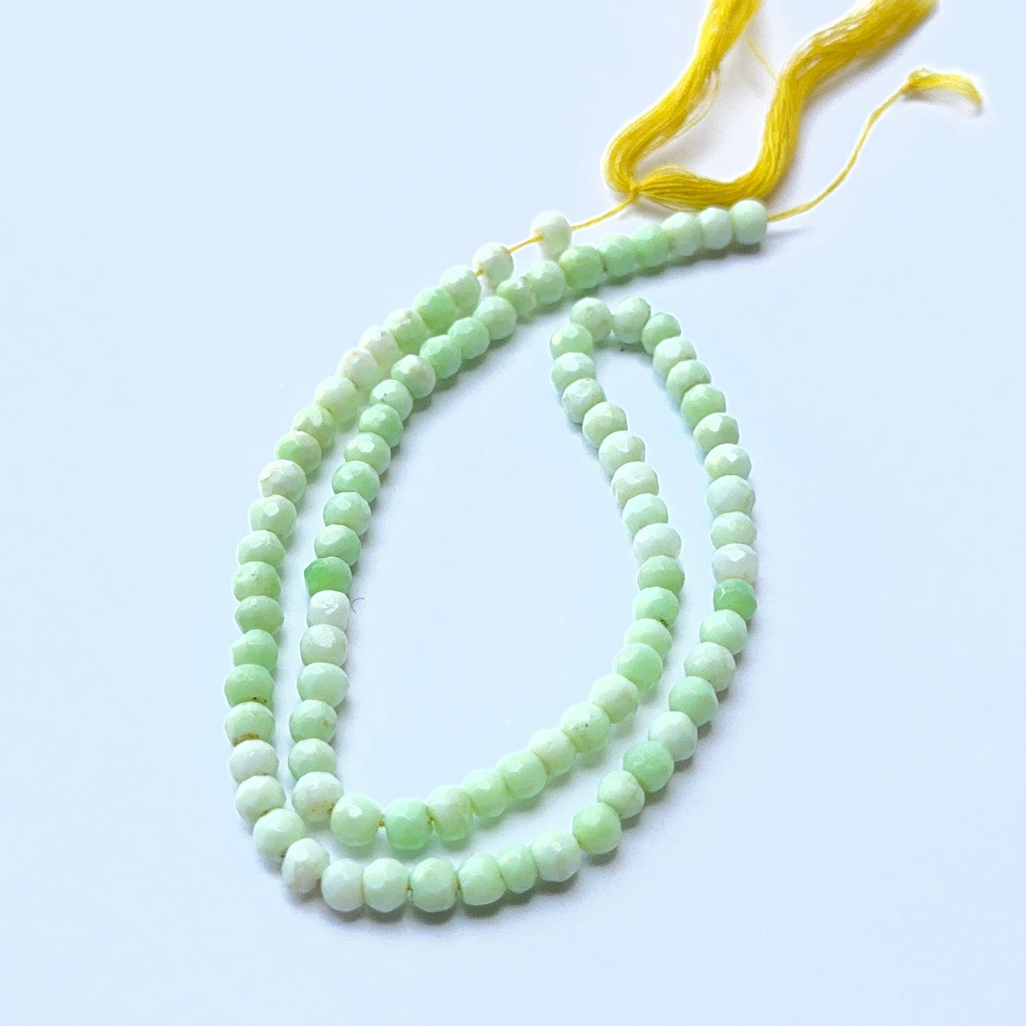Close‑up of Green Opal stone beads in faceted rondelle cut, highlighting gentle shimmer and natural patterns for handmade jewellery components.