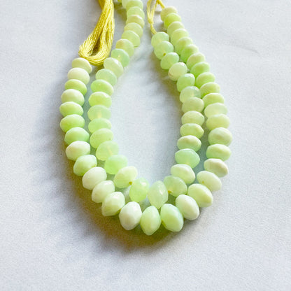 Neatly strung Green Opal faceted rondelles displayed in natural light.
