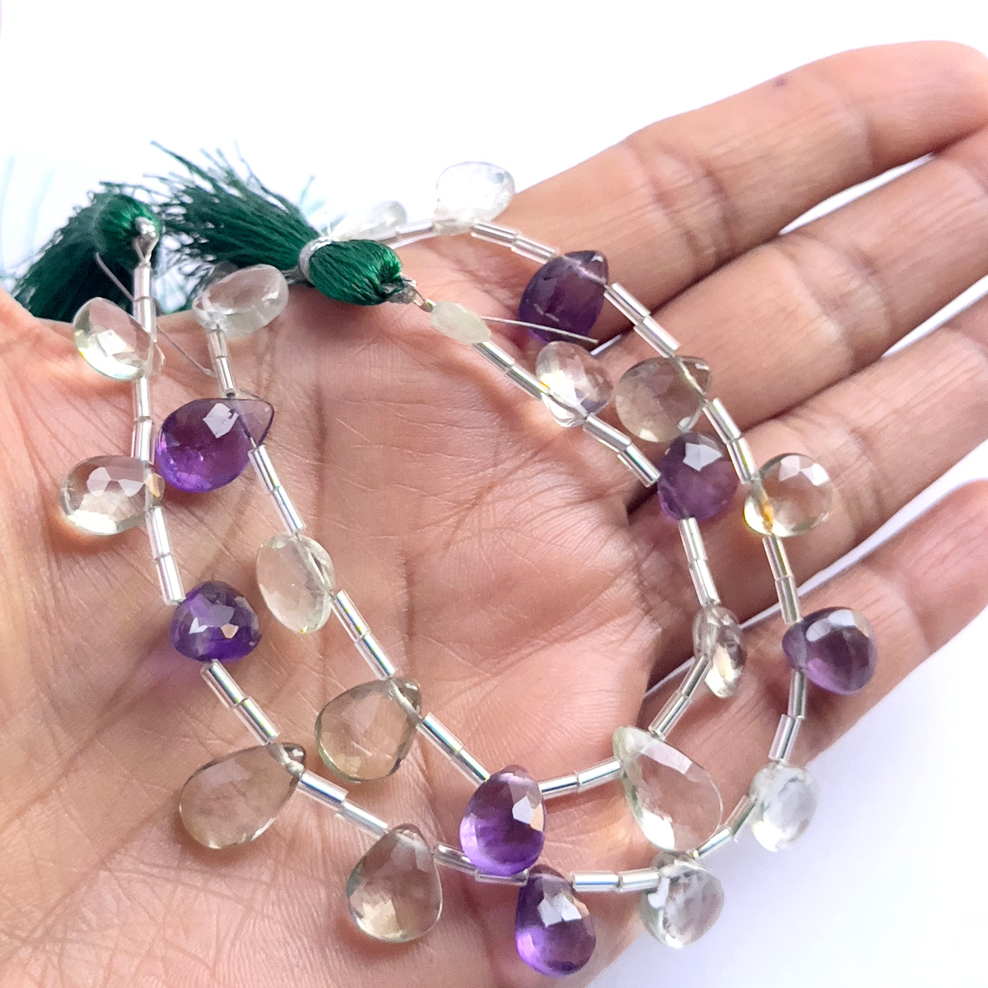 A person holds delicate strands of Green and Purple Amethyst beads, showcasing their smooth design.