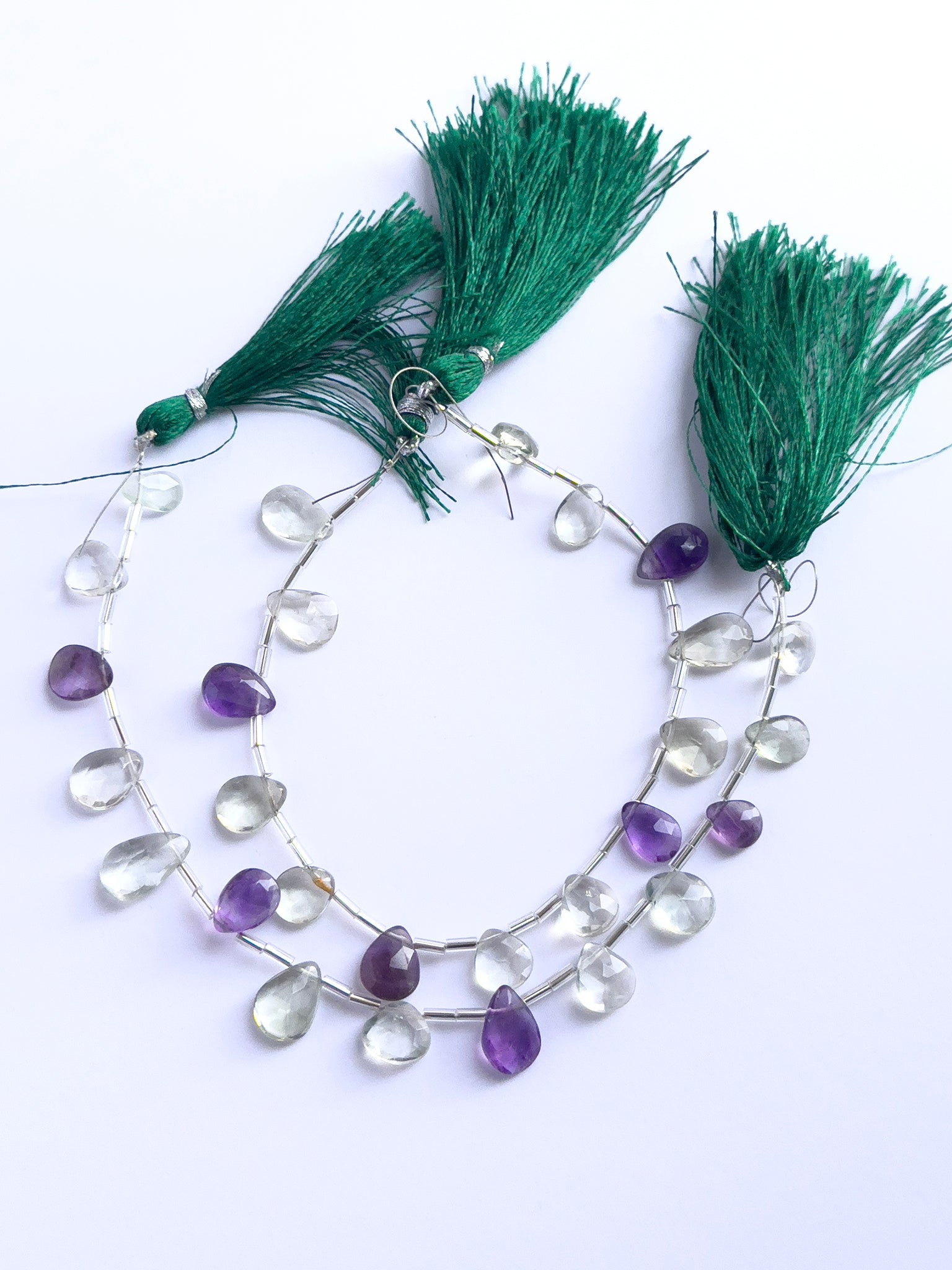 Handmade jewellery components featuring green and purple amethyst faceted briolette beads strung together.