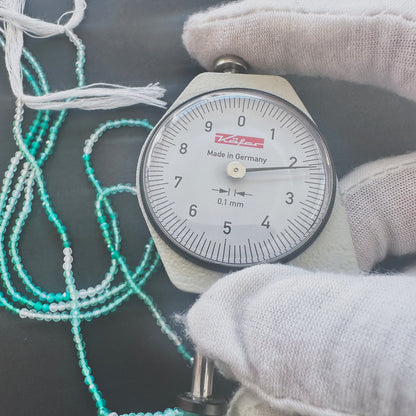 A dial gauge measures the Green Shaded Onyx faceted rondelle 2.2mm gemstone.