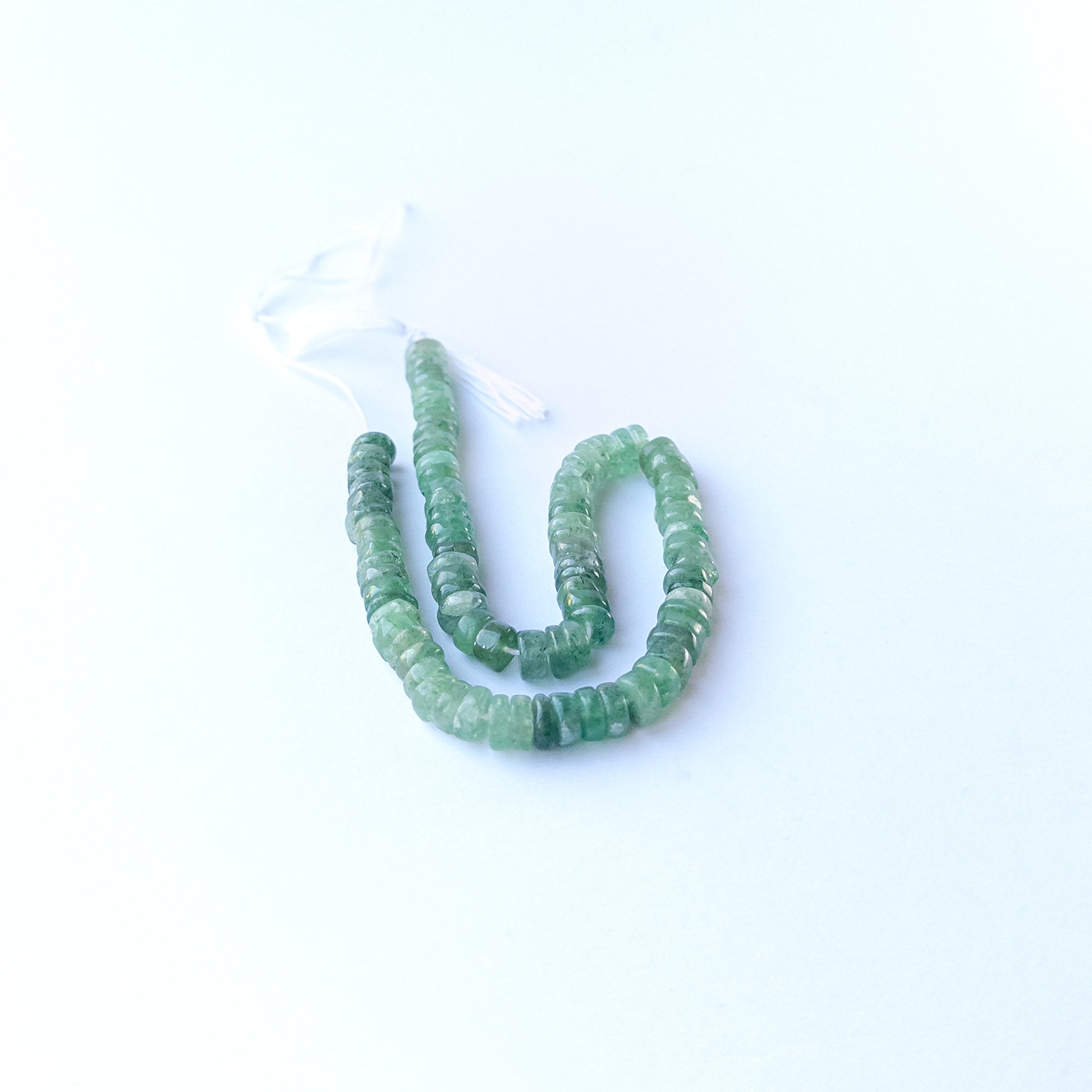 Green Strawberry Quartz smooth wheel gemstone beads arranged in a soft green strand for DIY jewellery.