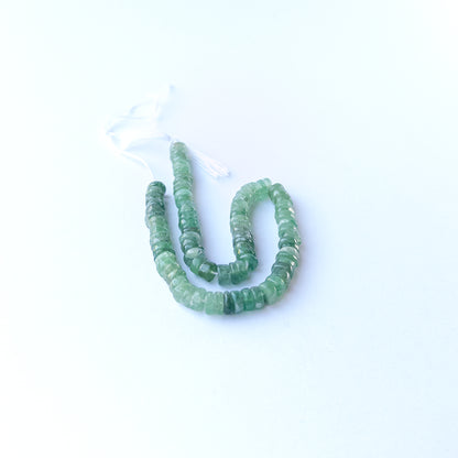 Green Strawberry Quartz smooth wheel gemstone beads arranged in a soft green strand for DIY jewellery.
