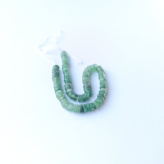 Green Strawberry Quartz smooth wheel gemstone beads arranged in a soft green strand for DIY jewellery.