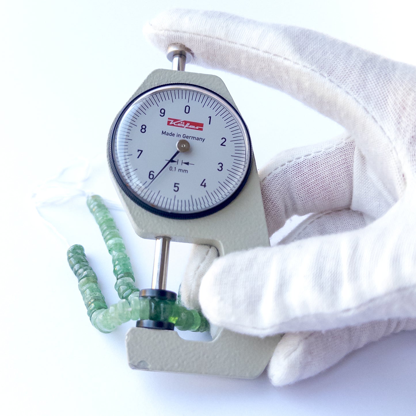A dial gauge measures the Green Strawberry Quartz smooth wheels 5.7–6mm gemstone.