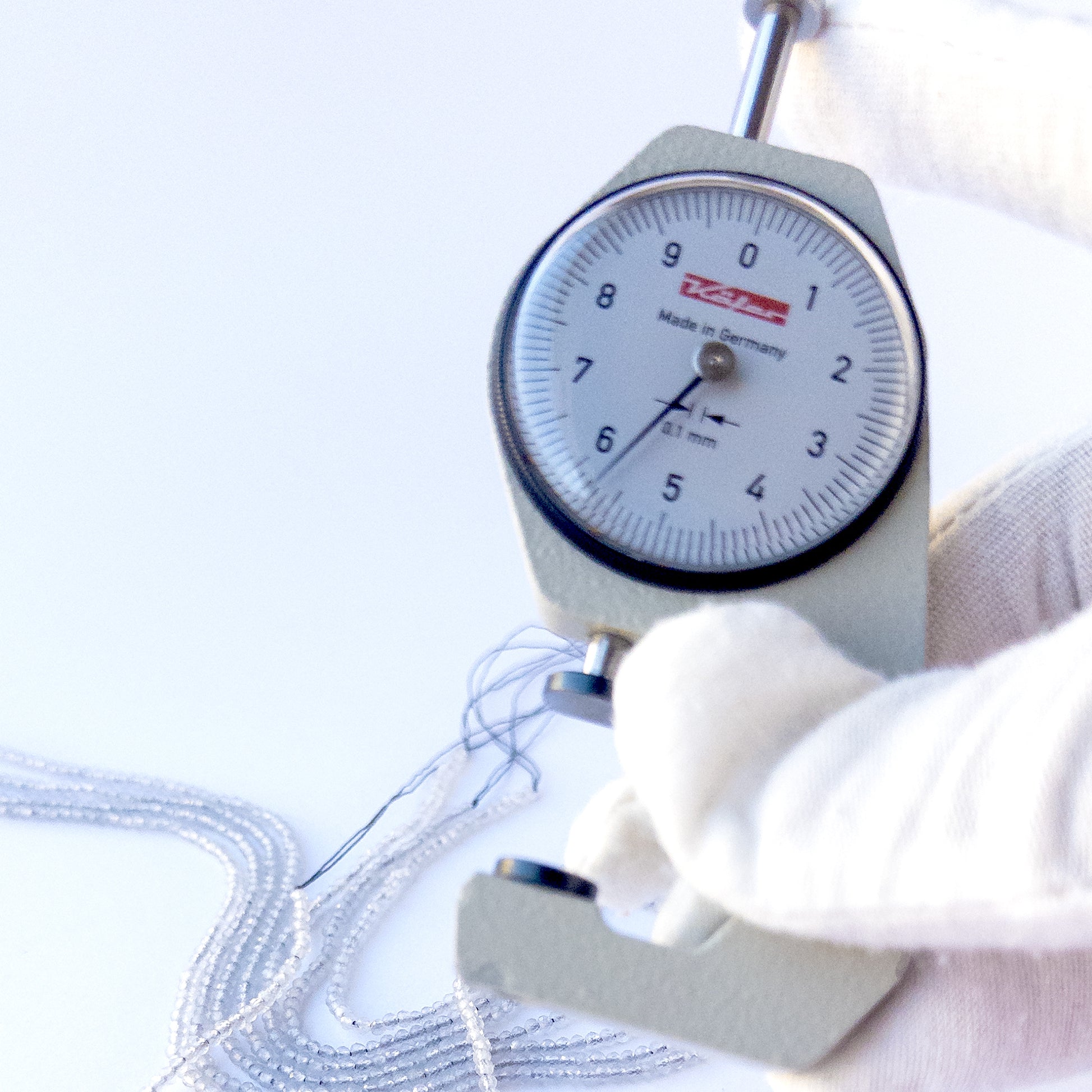 A dial gauge measures the Grey Chalcedony faceted rondelle 2.2mm gemstone.