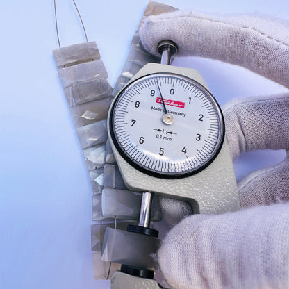 A dial gauge measures the Grey Moonstone faceted rectangle 21×9mm gemstone.