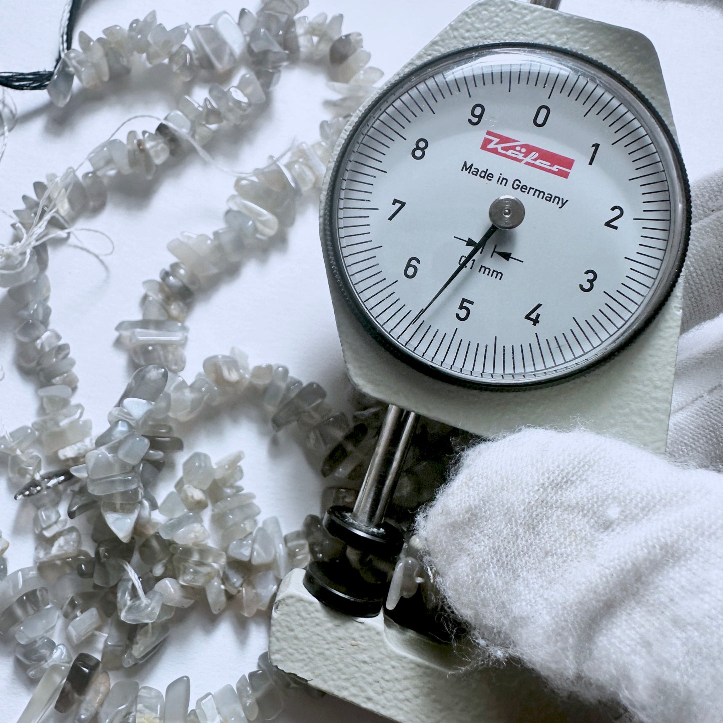 A dial gauge measures the Grey Moonstone smooth chip 4-9mm gemstone.