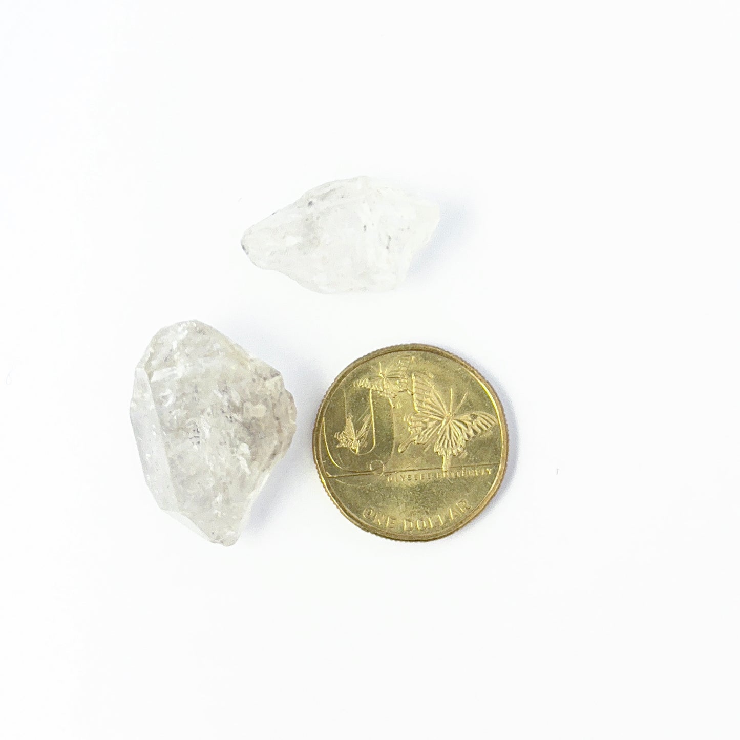 A coin is placed near delicate pieces of Herkimer Diamond rough for scale.
