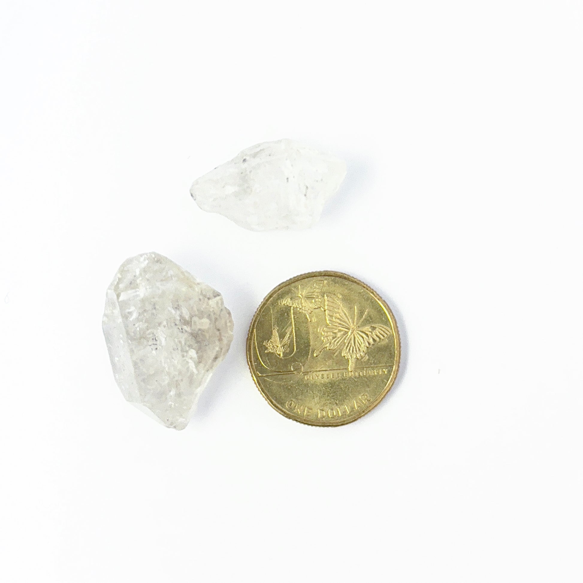 A coin is placed near delicate pieces of Herkimer Diamond rough for scale.