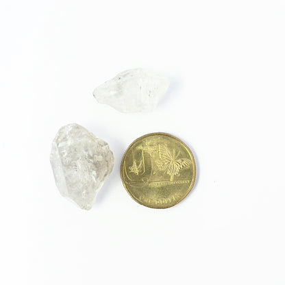 A coin is placed near delicate pieces of Herkimer Diamond rough for scale.