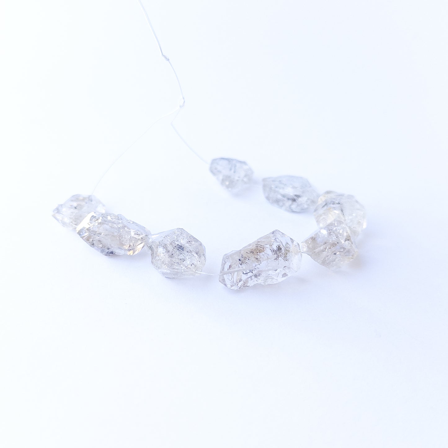 Herkimer Diamond gemstone beads arranged in a set of five, displaying their unique double‑terminated shape.