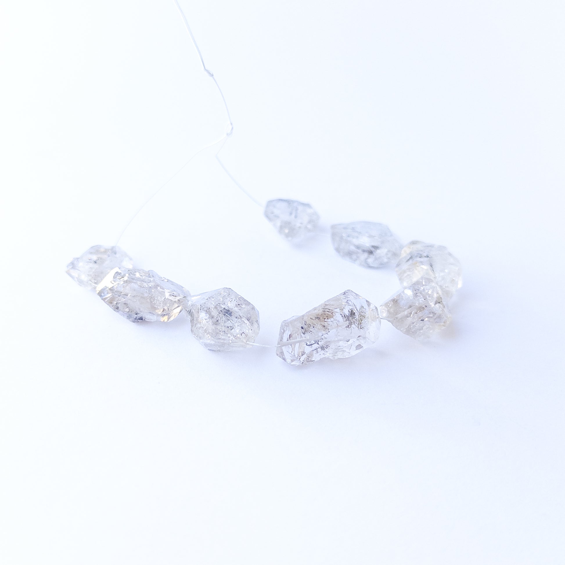 Herkimer Diamond gemstone beads arranged in a set of five, displaying their unique double‑terminated shape.