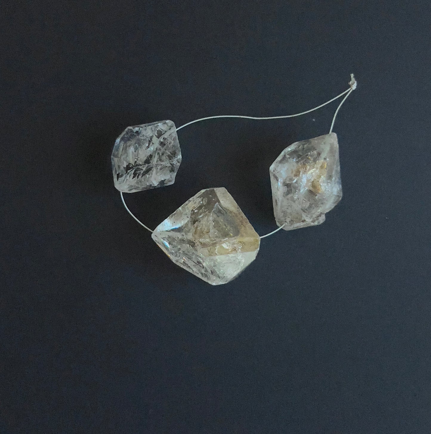 Close-up of 3 Herkimer Diamond stone beads featuring drilled holes and raw crystal texture.