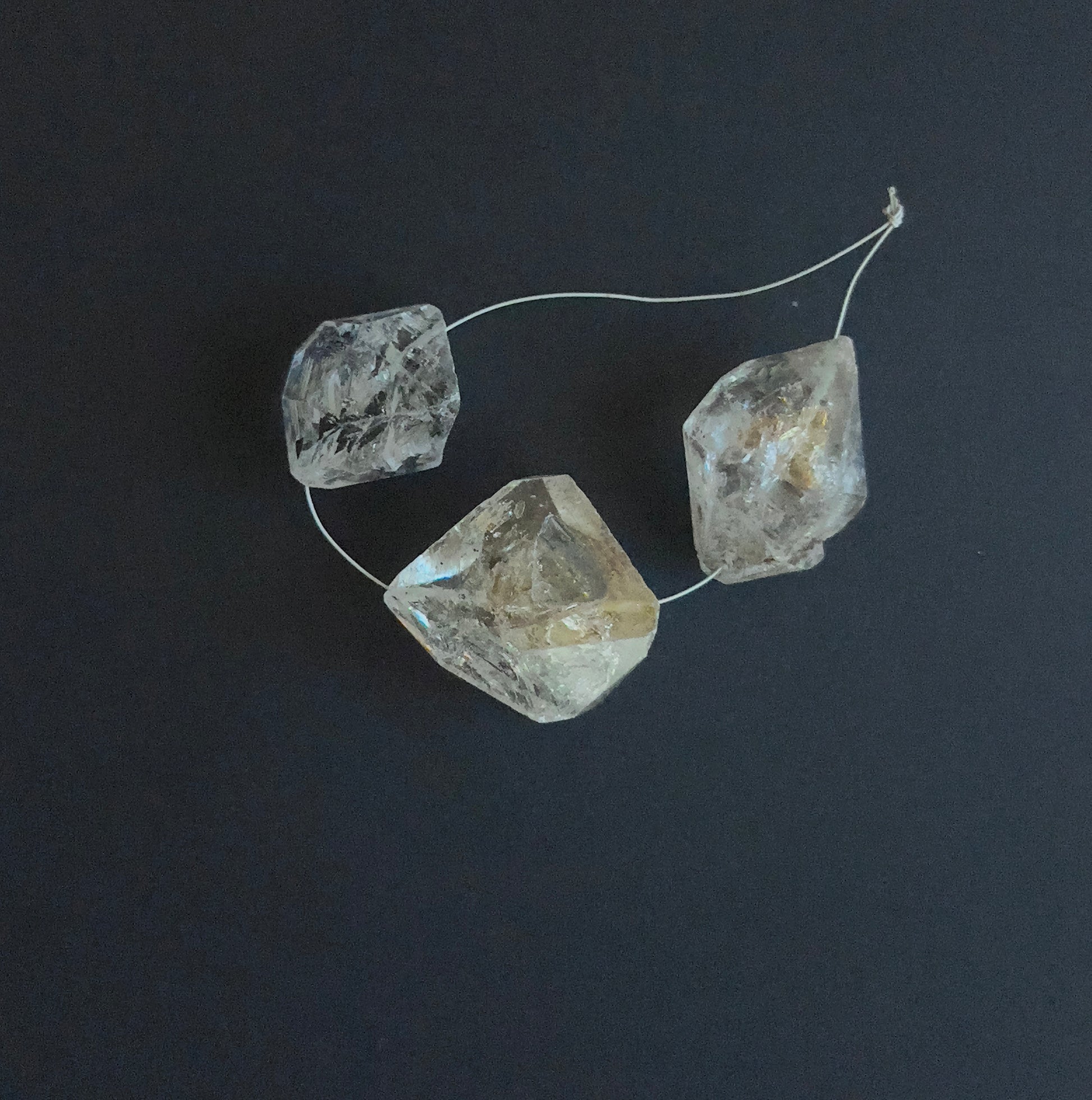 Close-up of 3 Herkimer Diamond stone beads featuring drilled holes and raw crystal texture.