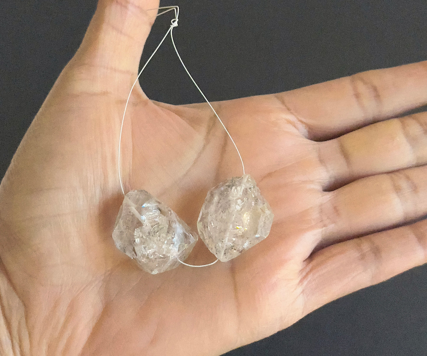 A person holds delicate strands of Herkimer Diamond beads, showcasing their smooth design.