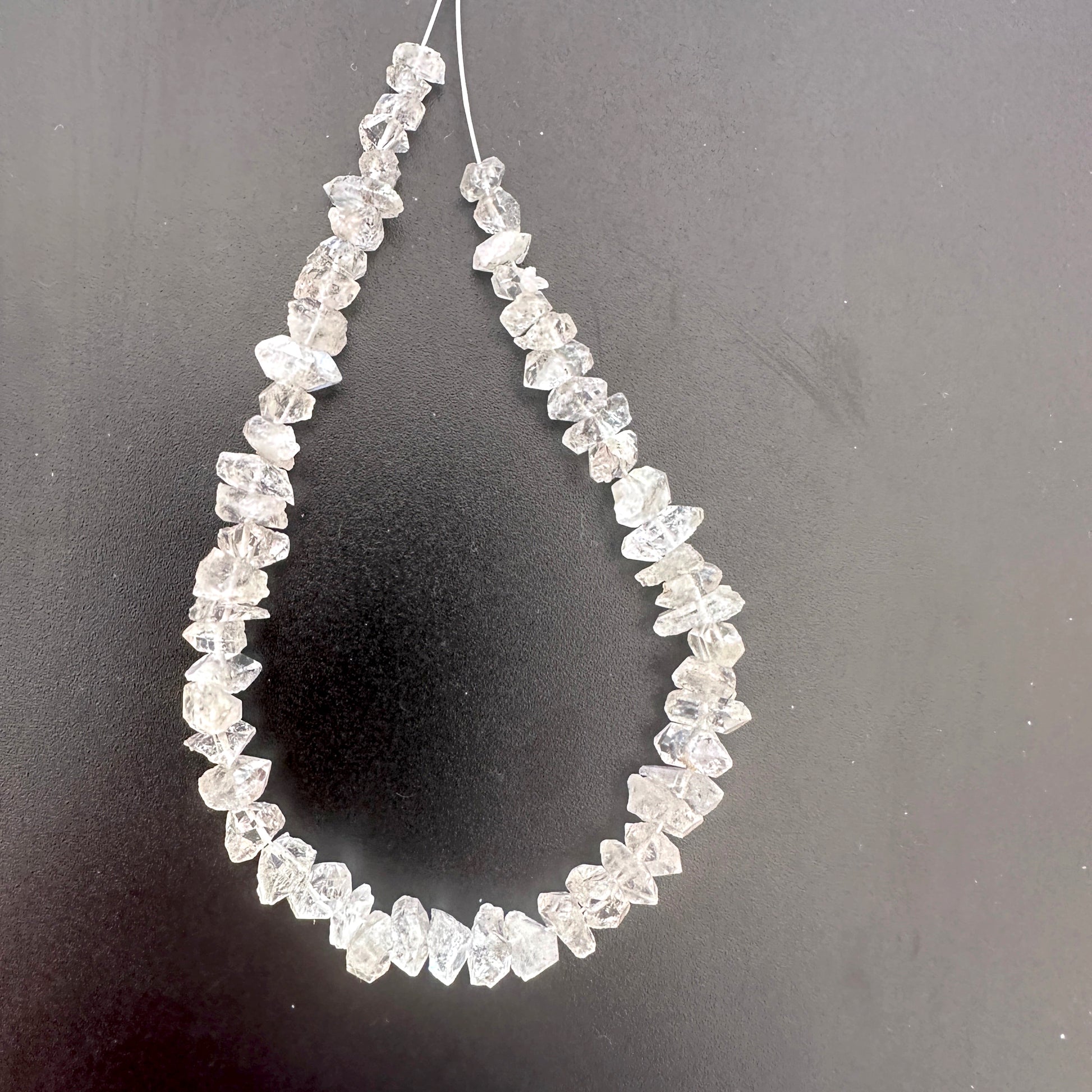 Herkimer Diamond rough beads with natural clarity and centre-drilled holes, arranged in a 57-piece pack.