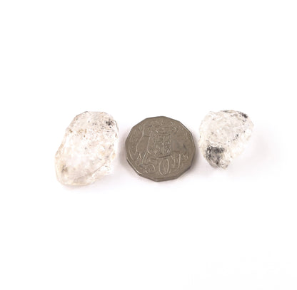 A coin is placed near delicate pieces of Herkimer Diamond rough for scale.