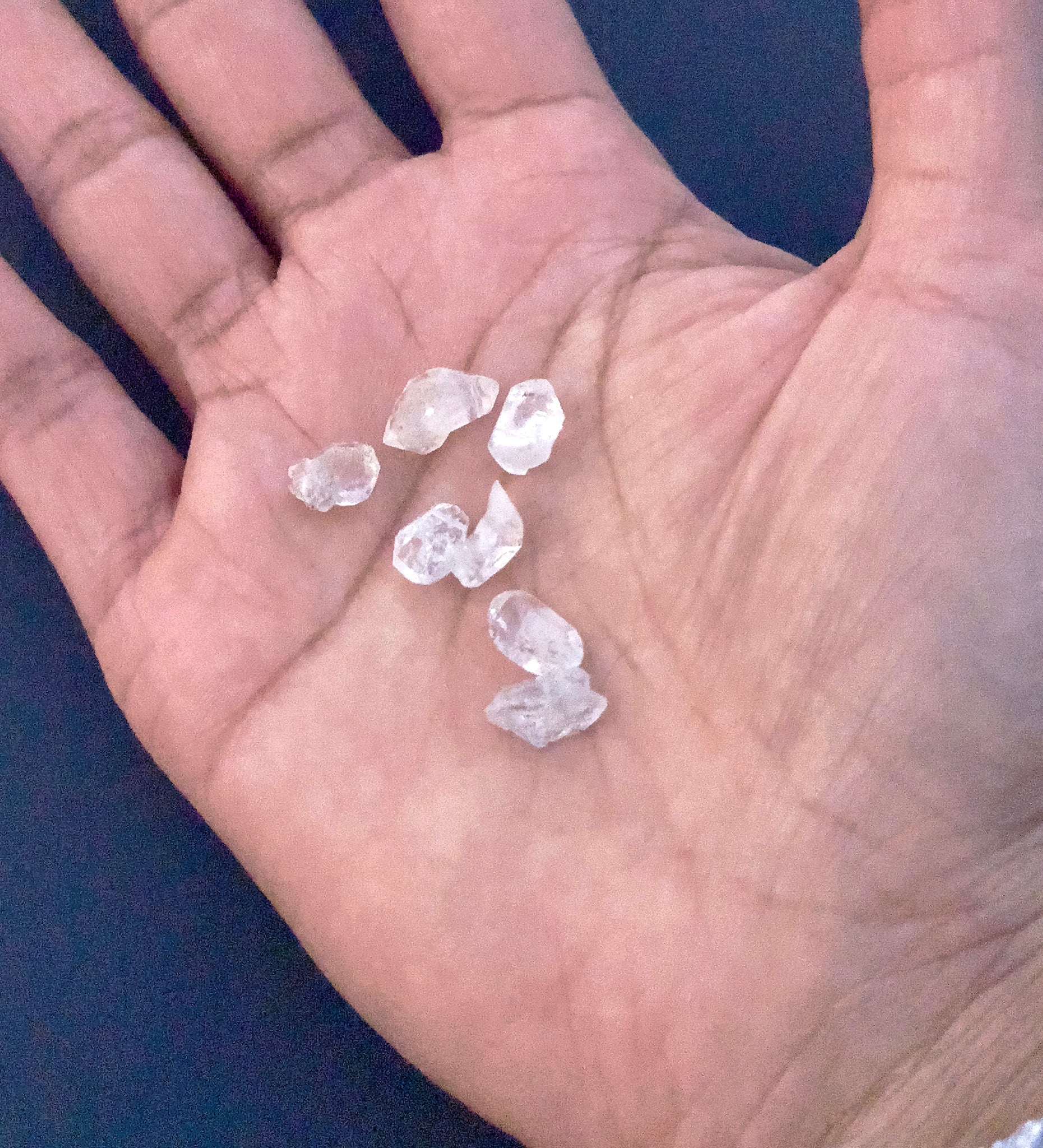 A person holds delicate strands of Herkimer Diamond beads, showcasing their raw design.