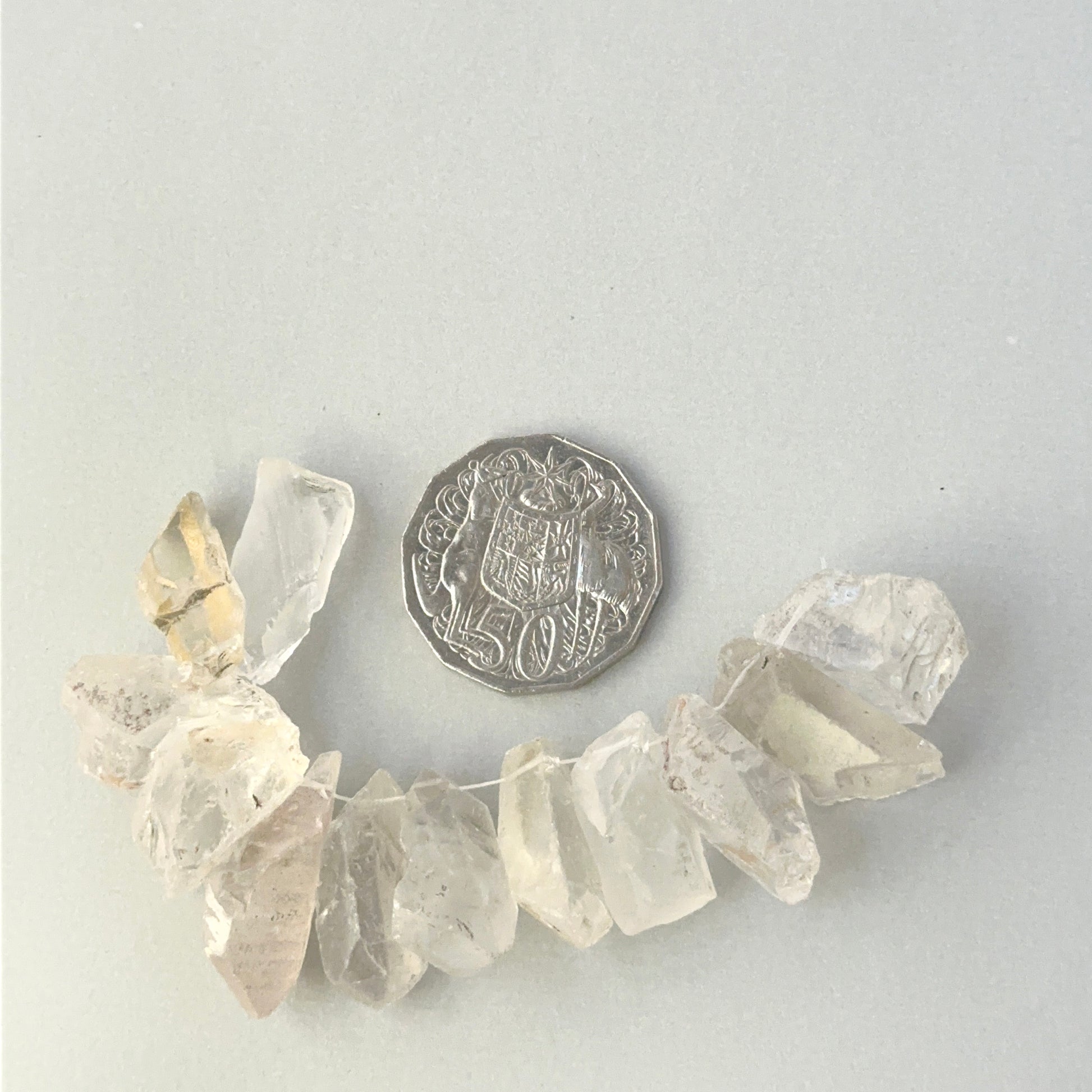 Clear oversized Herkimer Diamond crystal beads for bespoke wire wrapped jewellery gifts, placed near a coin for scale.